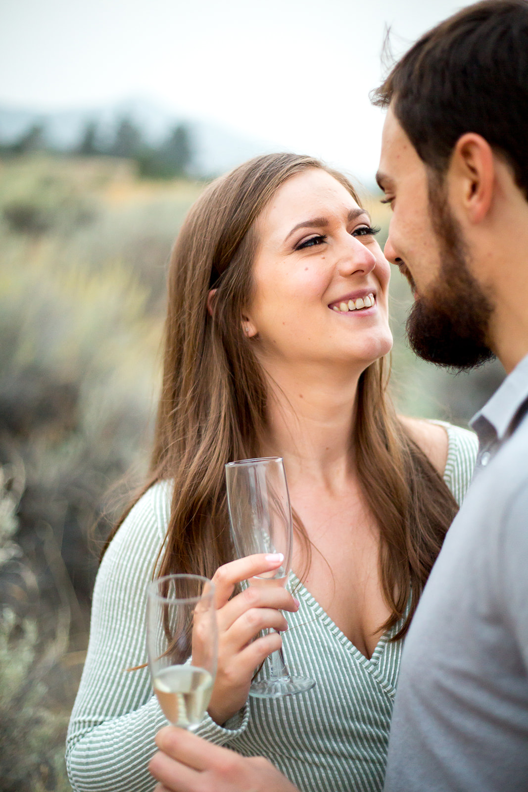 couple looks lovingly into one another's eyes as they each enjoy a glass of champagne outside