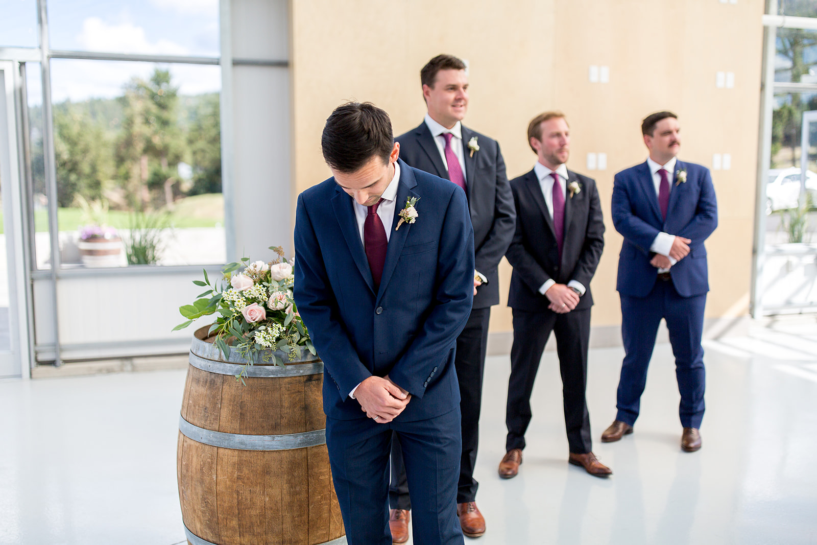 Groom stands at the altar inside a greenhouse waiting for his bride to arrive and walk down the aisle