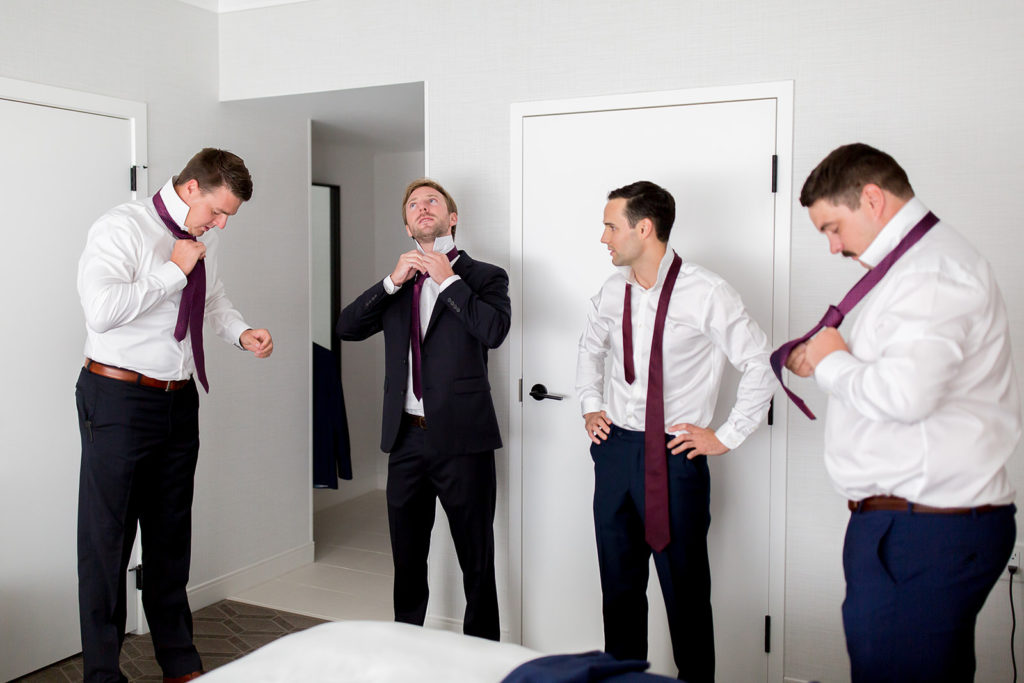 Groomsmen stand together inside their Kamloops hotel room preparing for a wedding ceremony at Monte Creek Winery
