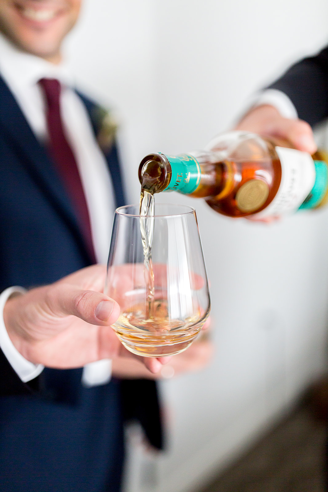 Detail shot of The Glenlivet Single Malt Scotch Whiskey being poured into a glass held by a groomsman