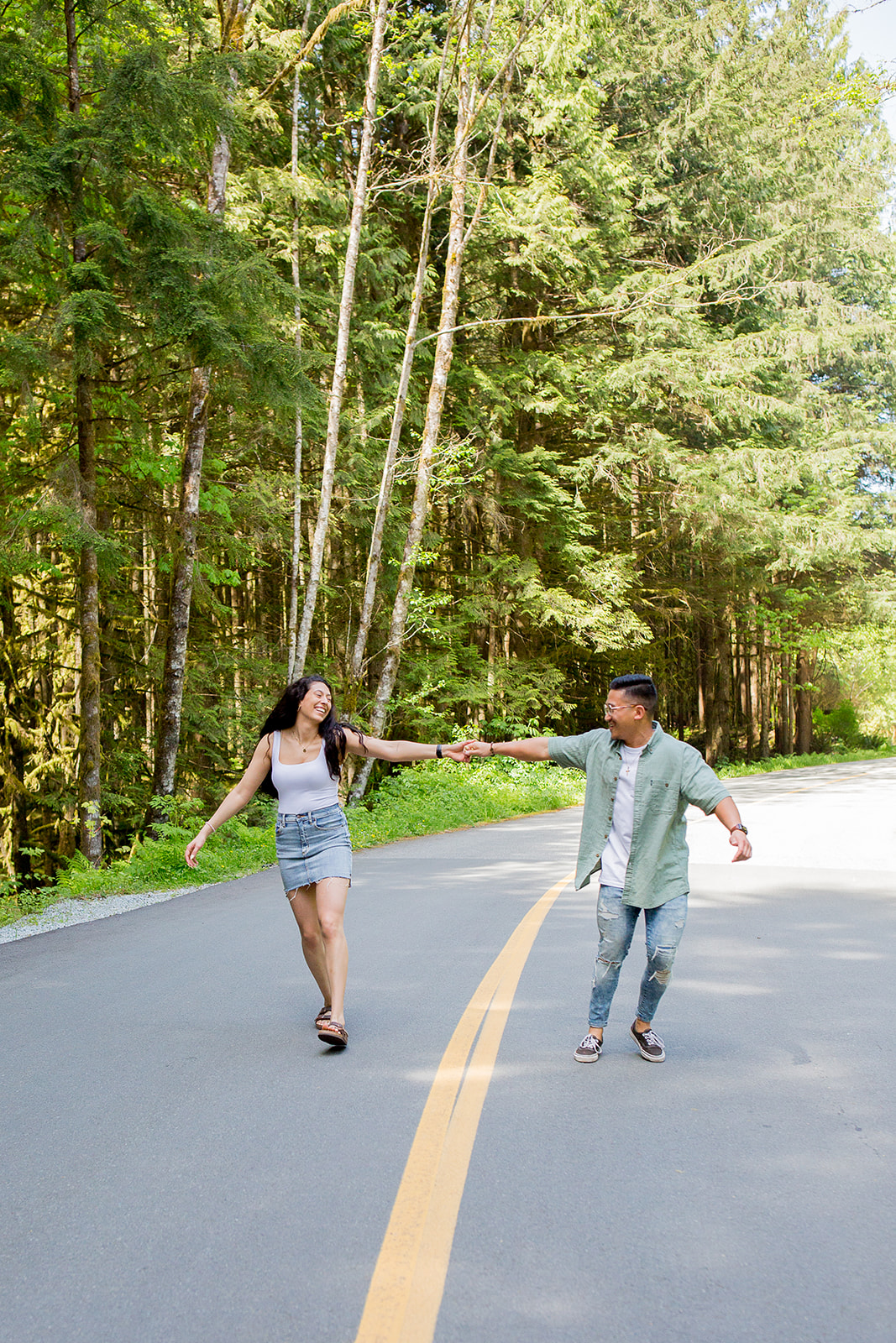 couple holds hands strolling down a quiet road in Golden Ears Provincial Park