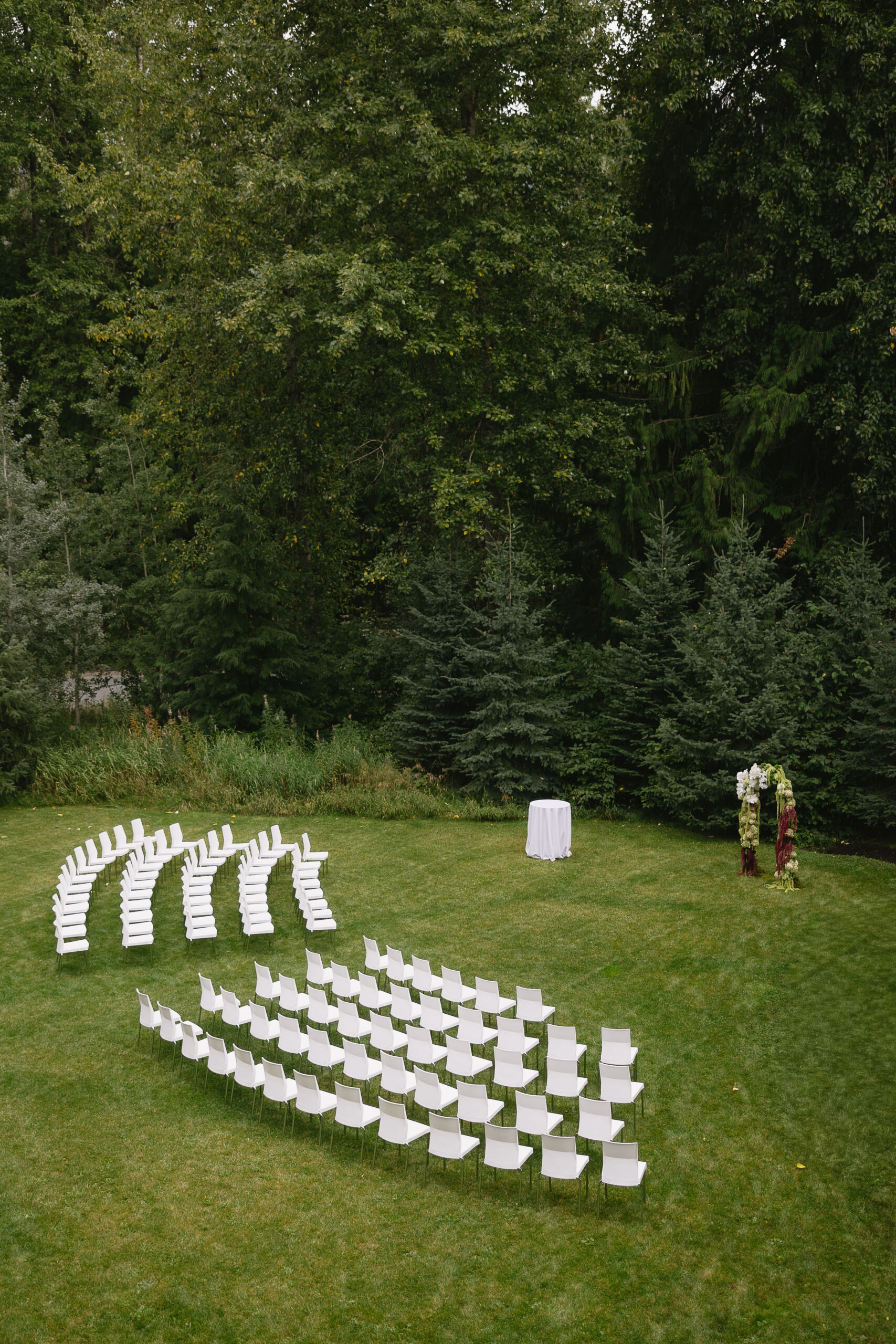 drone photo of the ceremony set up at the audain art museum lawn, set with white chair and a floral arch by beg florals whistler
